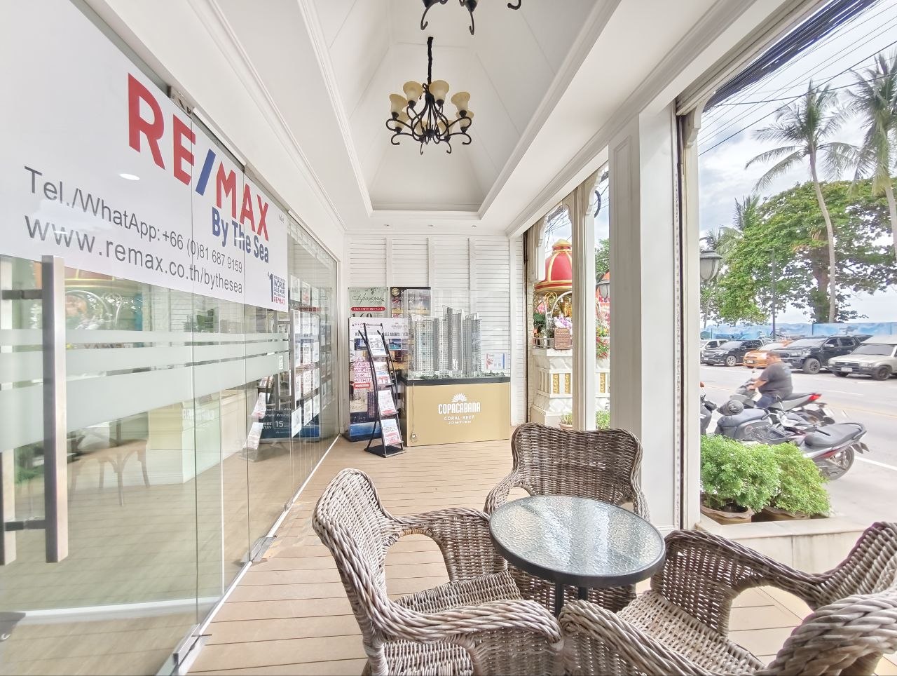 Covered patio seating beside the RE/MAX By The Sea office with beach-road view